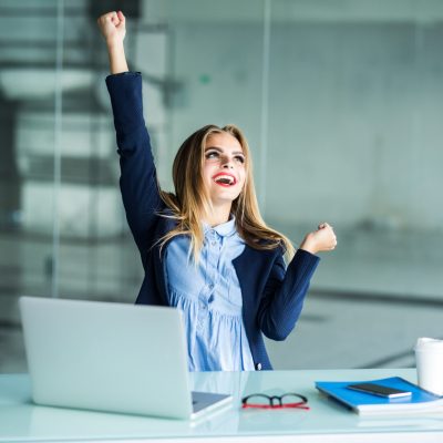 Successful young business woman with arms up at the office Successful business woman with arms up at the office